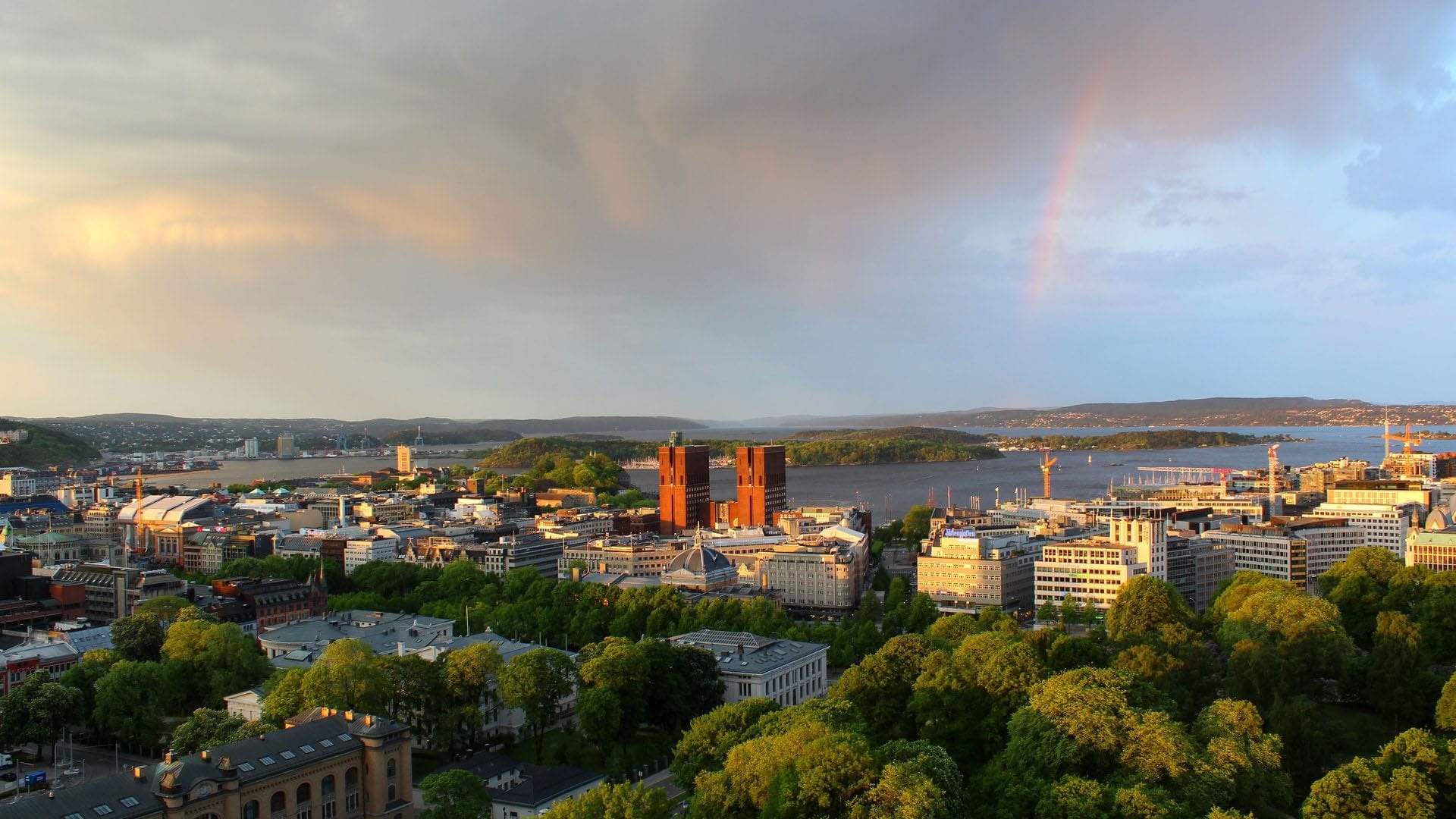 Cityscape with harbour and rainbow at sunset