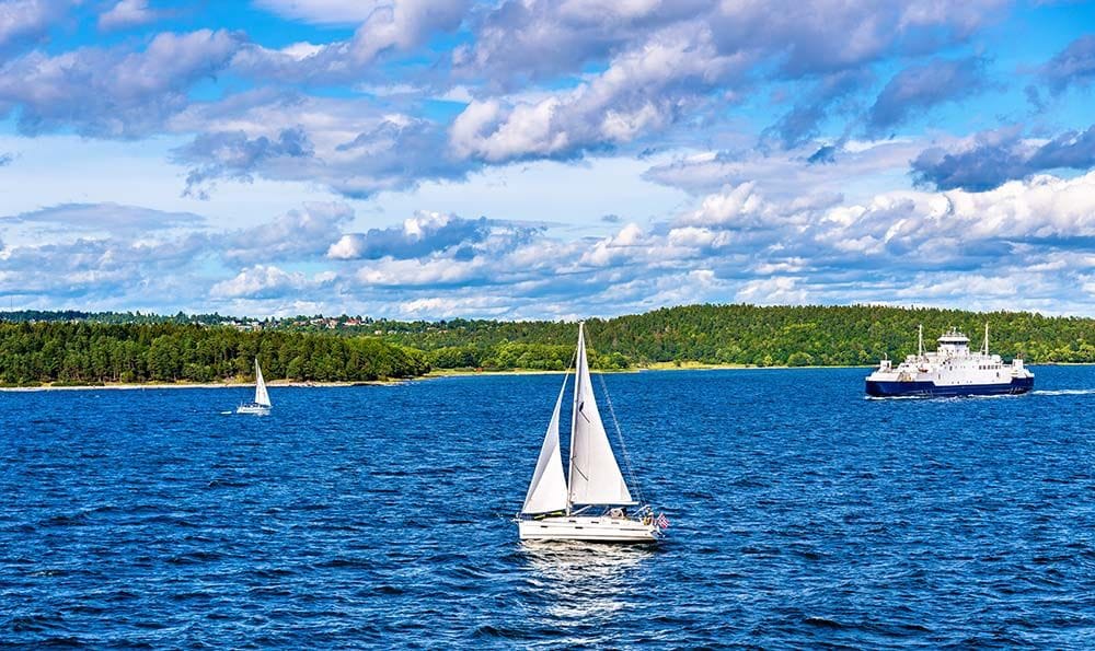 Sailboats and ferry on calm blue sea